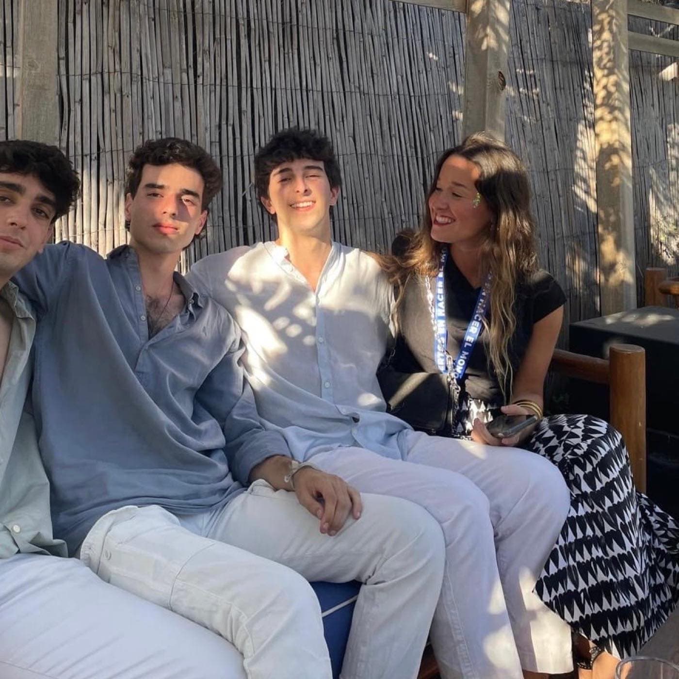 Grupo pequeño de cuatro amigos sentados juntos al aire libre en una terraza